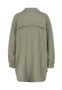 Long-sleeve shirt in olive green, made from textured fabric. Features a back yoke panel and button cuffs. Relaxed fit with rounded hem.