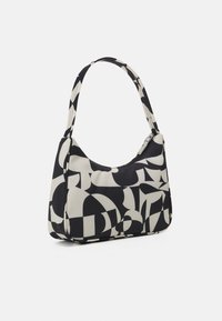 Liten axelväska med abstrakt svartvit geometrisk mönstring och dragkedjestängning på en enkel vit bakgrund.