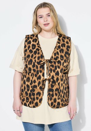 Ärmellose Weste mit Leopardenmuster in Schwarz und Braun, mit einer vorderen Bindeschließe und zwei Vordertaschen, getragen über einem beigen Hemd.