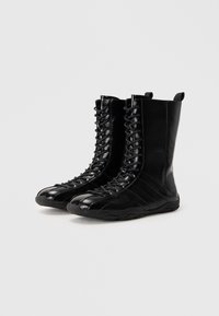 Černé kožené boty s vysokým svrškem, se šněrováním v přední části, texturovanými panely a gumovou podrážkou se zakřiveným designem.