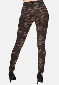 Dünne Camouflage-Jeans in Grün-, Braun- und Schwarztönen, mit hoher Taille, Gesäßtaschen und einem eleganten, dehnbaren Stoff.