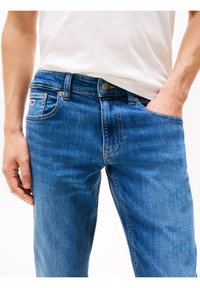 Jasnoniebieskie jeansy z dżinsu o prostym kroju, wyposażone w pięć kieszeni, naszywkę z logo marki oraz delikatne przetarcia na udach.