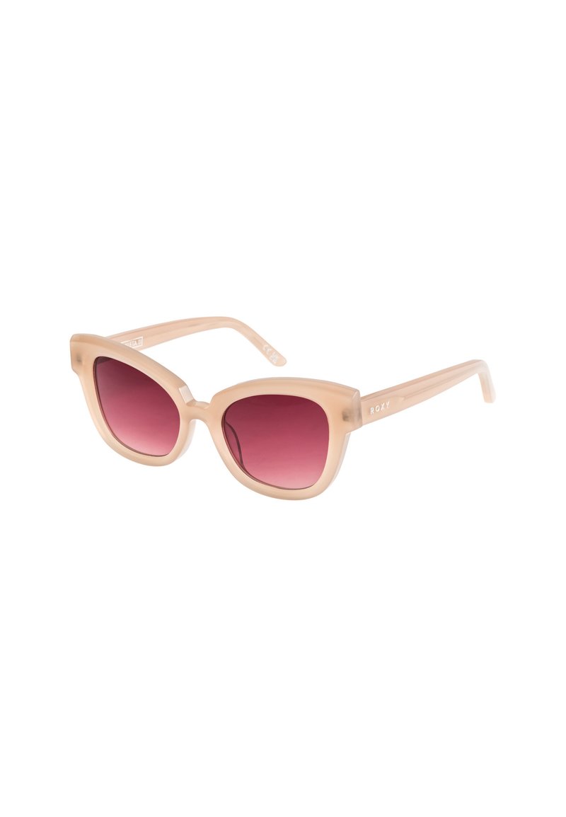 Gafas de sol estilo gato con un marco translúcido en tono nude y lentes rosa degradado. Diseño ligero de plástico con la marca Roxy en las patillas.
