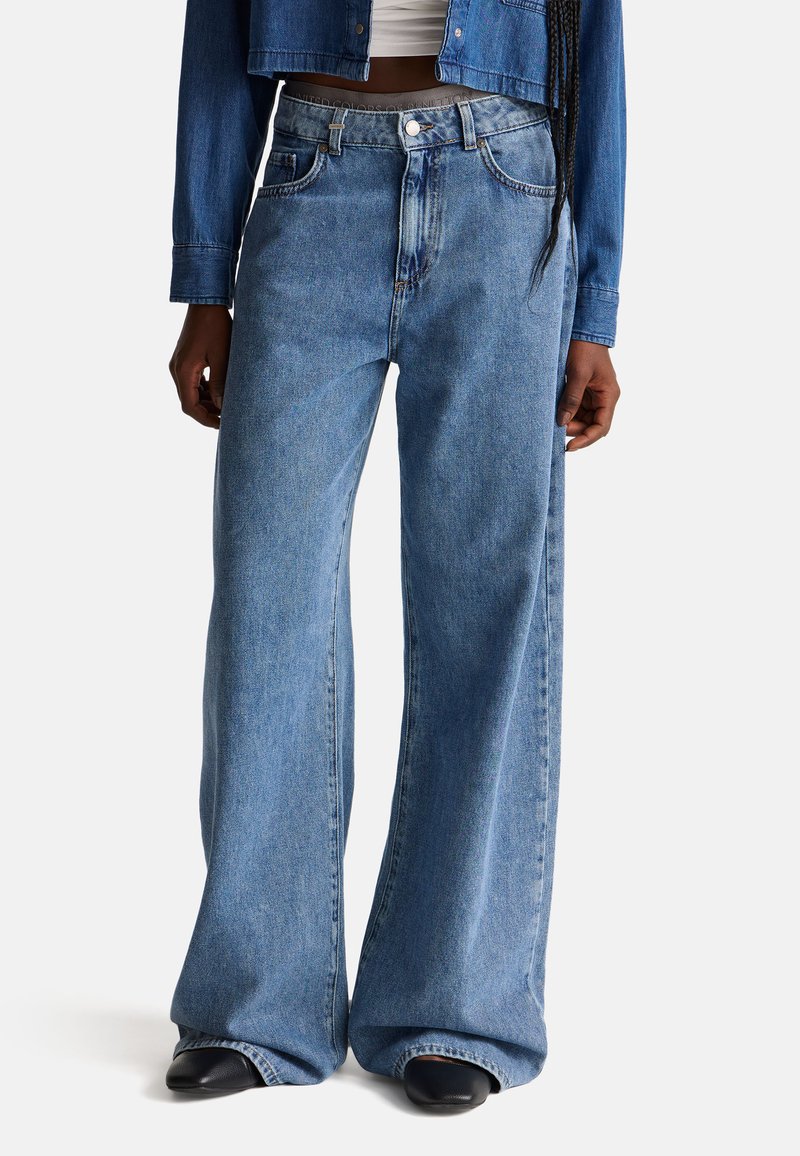 Wijdgevallen blauwe denim jeans met een hoge taille, voorzien van een sluiting met knoop aan de voorkant, zakdetails en een zachte, textuurafwerking.