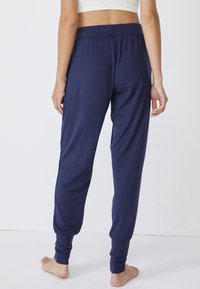 Marinblå, lätta joggerbyxor med en avslappnad passform, smalnande ärmar och elastisk midja, gjorda av mjukt, andningsbart material.