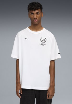 Hvid bomulds T-shirt med korte raglanærmer. Har et sort logo med "75" og "Formula 1" på brystet, samt et Puma-logo på ærmet.