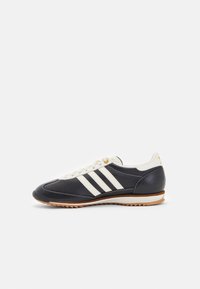 Navy leather sneaker with white three stripes and cream laces. Features a sleek design and rubber sole with a textured grip.