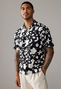 Korte mouwen shirt in zwarte stof met een wit bloemenpatroon. Met knoopsluiting, ontspannen pasvorm en een gladde textuur.