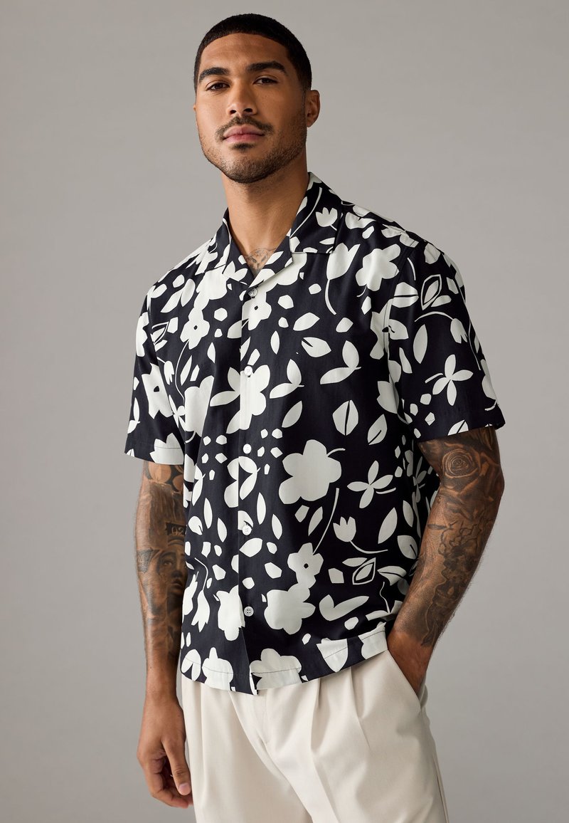 Korte mouwen shirt in zwarte stof met een wit bloemenpatroon. Met knoopsluiting, ontspannen pasvorm en een gladde textuur.