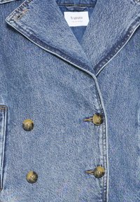 Veste en denim à double boutonnage de couleur bleu clair avec une finition texturée, dotée de boutons dorés, d'un col à revers et de surpiqûres.