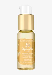 Bumble and bumble Styling Oil in een transparante gouden glazen fles met een witte pompdeksel, reliëflogo en minimalistisch etiketontwerp.