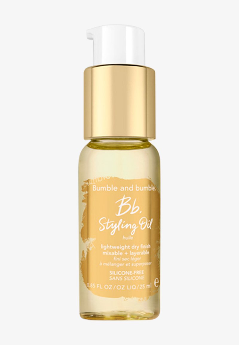 Bumble and bumble Styling Oil in een transparante gouden glazen fles met een witte pompdeksel, reliëflogo en minimalistisch etiketontwerp.