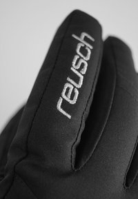 Sorte isolerede handsker med et tekstureret stof og et fremtrædende hvidt "reusch" logo broderet på manchetten.