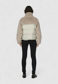 Fleece- og polstret jakke i beige og lysegrå. Har høy krage, lange ermer, og en teksturert overflate med blokkdesign.