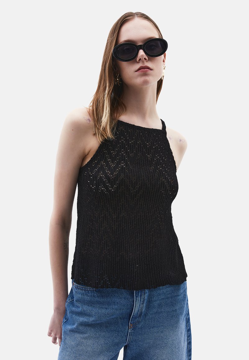 Top in maglia nera con un motivo testurizzato, scollo a barca e spalline sottili, abbinato a jeans di denim blu a vita alta.