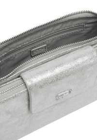 Srebrny portfel na zamek błyskawiczny o gładkim, metalicznym wykończeniu. Posiada wiele przegródek, wyściółkę z tkaniny oraz logo na przedniej stronie.