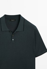 Mörkgrön polo skjorta med klassisk krage, utrustad med tre knappslå och kontrasterande kantdetaljer. Tillverkad av mjukt texturerat tyg.