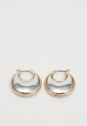 Petites boucles d'oreilles en forme de créole avec un bord extérieur en or et une surface intérieure en argent brillante et réfléchissante, présentées côte à côte sur un fond blanc.