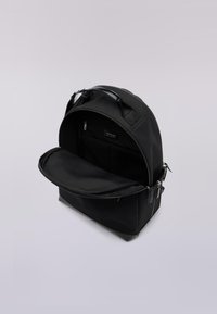 Černý batoh s zaobleným tvarem a hladkým nylonovým povrchem. Otevřený, s prostornou přihrádkou a síťovanou kapsou na organizaci.