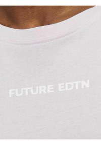 T-shirt grigio chiaro con scollatura rotonda e maniche corte. Sul davanti è presente la scritta "FUTURE EDTN" in lettere bianche in rilievo. Texture morbida.