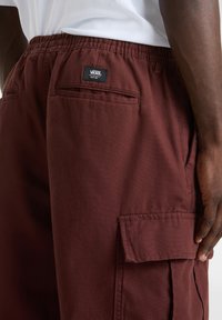 Bordeauxkleurige cargoshorts met een elastische tailleband, zijzakken en een genaaid VANS-label op de achterkant. Duurzaam, gestructureerd materiaal.
