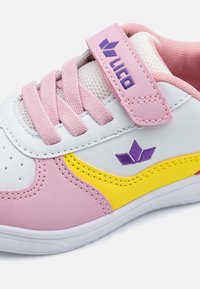 Tennised, mis sisaldavad valgeid, roosaid ja kollaseid sünteetilisi materjale. Kerge võrgust keel, lilla logo, perforatsiooniga varvas ja Velcro rihm.