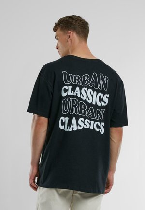 Fekete, bő szabású pamut póló, melynek hátsó részén stilizált fehér szöveg olvasható: "URBAN CLASSICS".