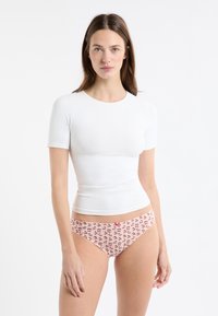 Biały dopasowany top z krótkim rękawem w połączeniu z różową, wzorzystą bielizną z małymi motywami wiśni i różową kokardką.