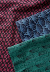 Tres muestras de tela en tonos de burdeos, azul y verde, con patrones distintos: ovalados, en forma de abanico y hexagonales.