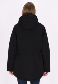 Zwarte hoodie-jack met een getailleerde taille, lange mouwen en een iets verlengde achterkant. Soepele textuur met minimale hardware-details.