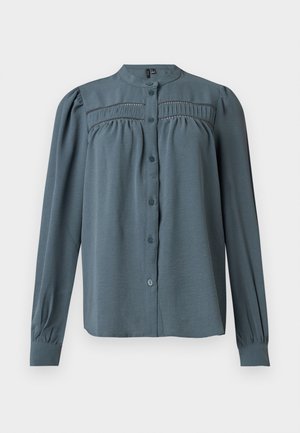 Blouse à manches longues bleu ardoise avec col montant, devant à boutons, détails plissés et en dentelle sur la poitrine, et manches à poignet.