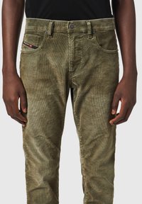 Pantalones de pana verde oliva con corte recto, que presentan bolsillos frontales, cierre de botón y una textura sutil.