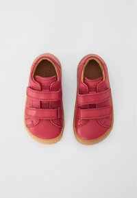 Red leather shoes with Velcro straps, rubber soles, and a textured finish. Light brown accents on the sole enhance the design.