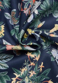 Donker marineblauw stof met een bloemenpatroon van gele, roze en groene bloemen, een gladde textuur en een lichte glans.
