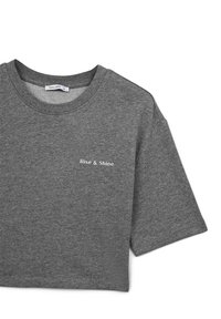 T-shirt grigio a maniche corte con testo "Rise & Shine" in bianco. Tessuto morbido, collo a giro, vestibilità casual con un design leggermente accorciato.