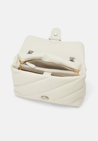 Crème-kleurige handtas met een gestructureerd, geborduurd ontwerp, een magnetische drukknoop sluiting en een rits binnenzak. Gladde kunstlederen materiaal.