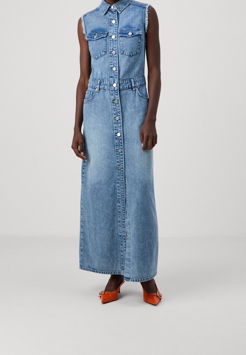 Robe maxi en denim avec design sans manches, col, deux poches poitrine et fermeture à boutons. Tissu bleu clair avec finition délavée.