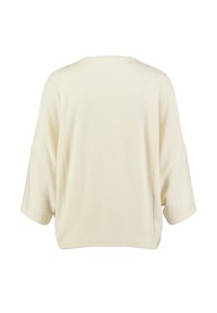 Top recortado color crema en una tela suave y texturizada; ajuste amplio y relajado con mangas tres cuartos y un escote redondeado.
