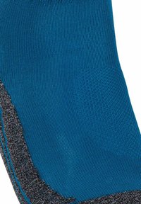 Primer plano de un calcetín azul y gris que muestra patrones de punto texturizados y área de talón reforzada.