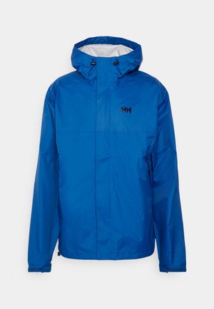 Chaqueta impermeable azul con capucha, con un logo negro en la parte superior izquierda. Dos bolsillos laterales y dobladillo ajustable. Textura lisa y ligera.
