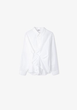 Camicia bianca a maniche lunghe con colletto a punta, caratterizzata da un dettaglio arricciato e una parte anteriore con volant, realizzata in un tessuto morbido. Chiusura con bottoni inclusa.