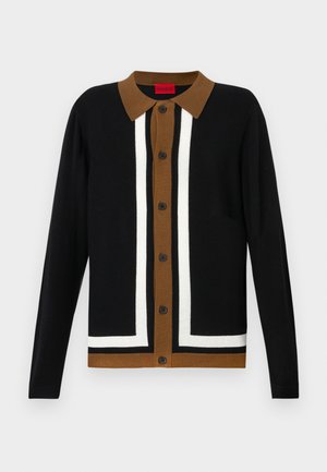 Svart cardigan med brun krage, med et hvitt stripemønster og knappelukking. Strukturert stoff med lange ermer og trimmelig kant.