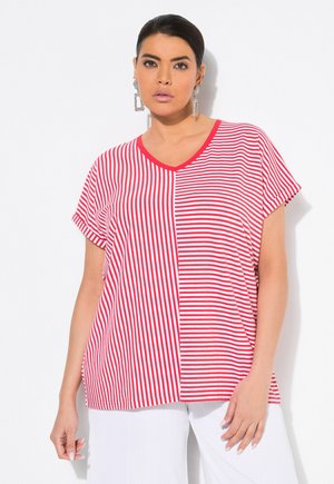 Top a maniche corte a V in rosso e bianco con una sezione centrale rossa a tinta unita. Tessuto leggero, vestibilità rilassata e maniche arrotolate.