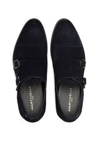 Zapatos de ante azul marino con dobles hebillas, puntera redonda y detalles de costura sutiles. El interior es de cuero texturizado.