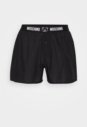 Black boxers with a button closure, featuring an elastic waistband with "Moschino" and a bear logo. Made from smooth fabric with a loose fit.