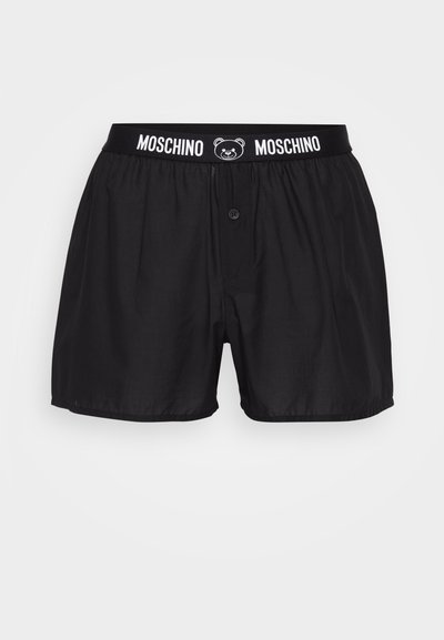 Boxers pretos com fecho de botão, apresentando um cós elástico com "Moschino" e um logo de urso. Feitos de um tecido suave com corte solto.