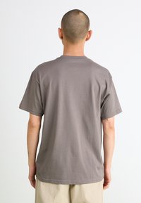 Kortermet T-skjorte i grå bomull, med rund hals og avslappet passform. Glatt tekstur med et rent, minimalistisk design.