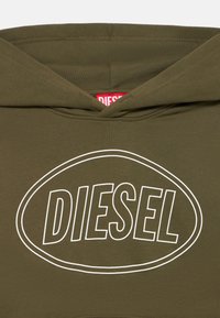 Πράσινο ελιάς φούτερ με κουκούλα, με λευκό περιγραμμικό οβάλ λογότυπο και έντονο κείμενο "DIESEL" στο κέντρο του στήθους.