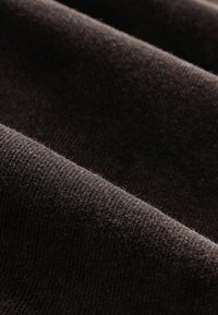 Must-black, pehme materjal ribadega tekstuuriga, millel on mitmed voldid. Materjal näeb välja paks ja karvane, mis suurendab selle taktiilset omadust.