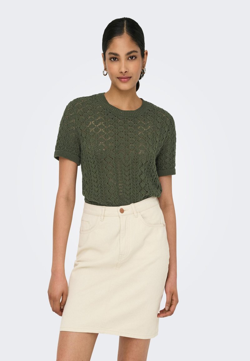 Knit green short-sleeve sweater with a textured diamond pattern, paired with a light beige denim skirt featuring a single button closure.